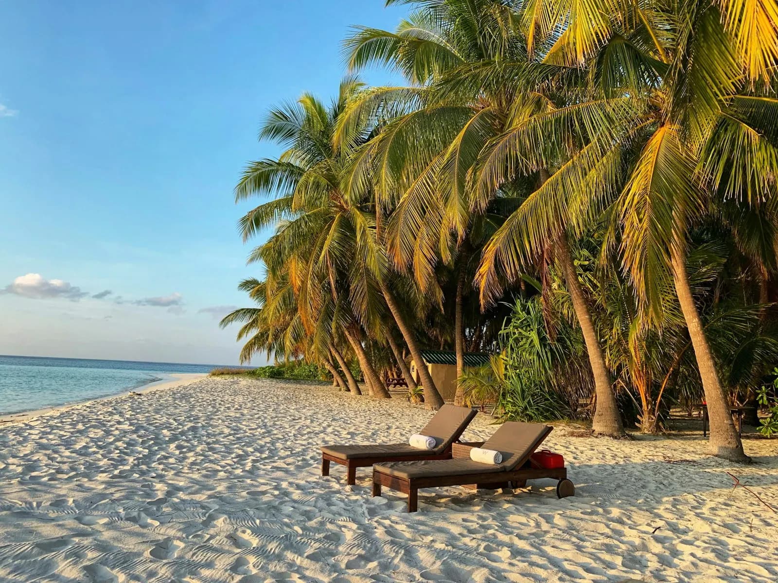 Two wooden loungers on a white sand beach